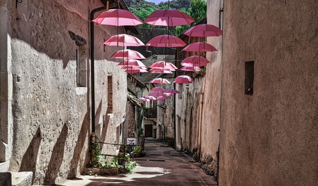 Розовые зонтики украшают узкую улицу