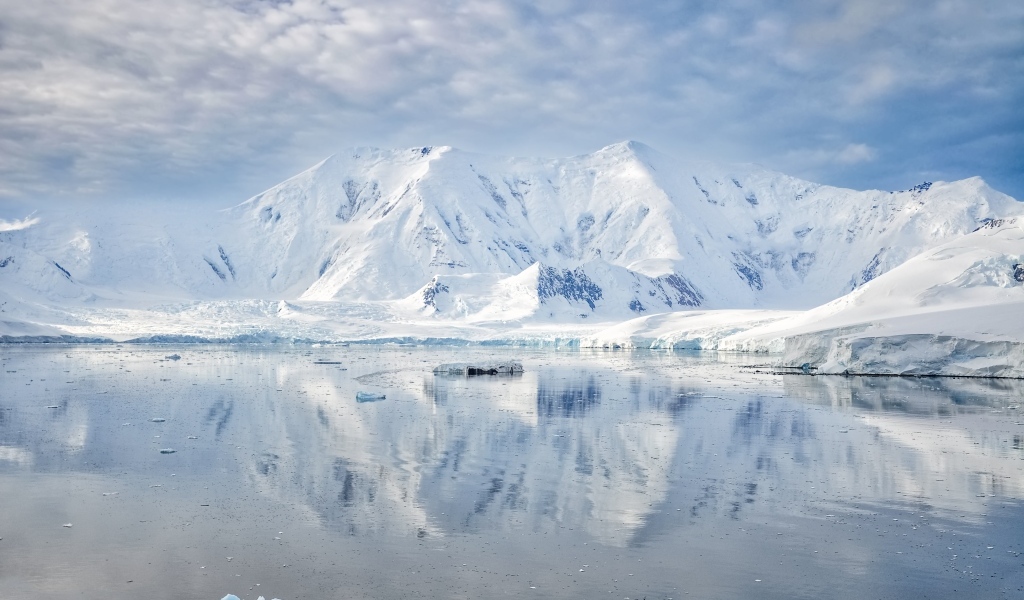 Заснеженные горы под белыми облаками у океана, Антарктида 