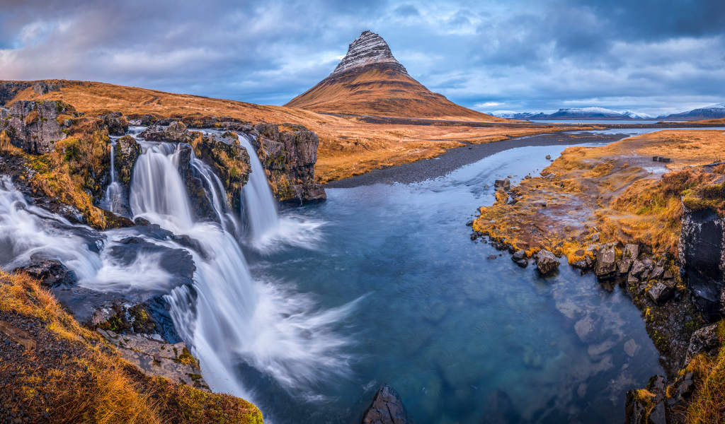Вид на реку, водопад и гору Киркьюфетль под пасмурным небом Исладнии