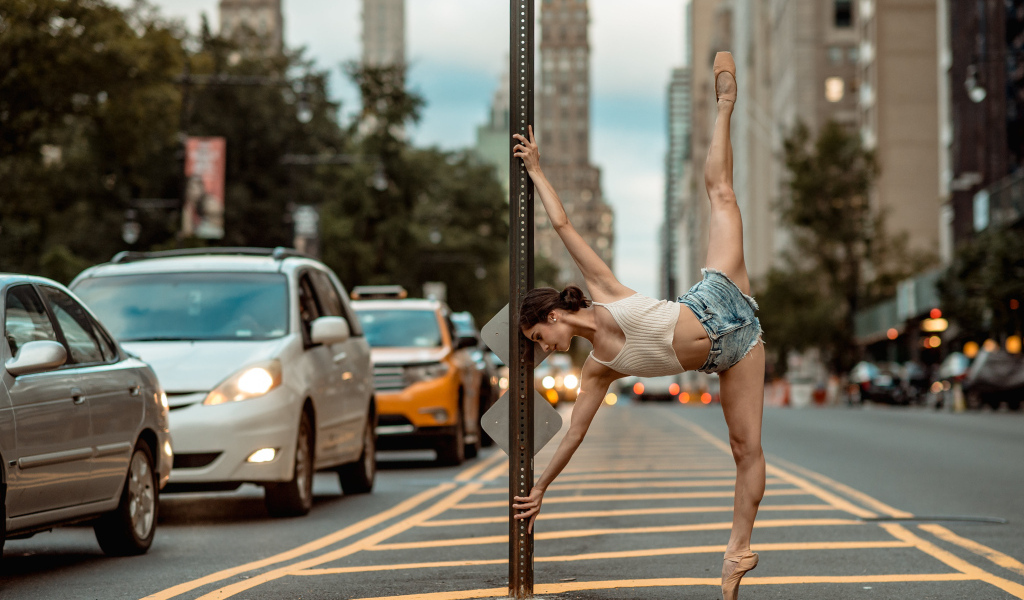 Девушка делает шпагат у столба в городе