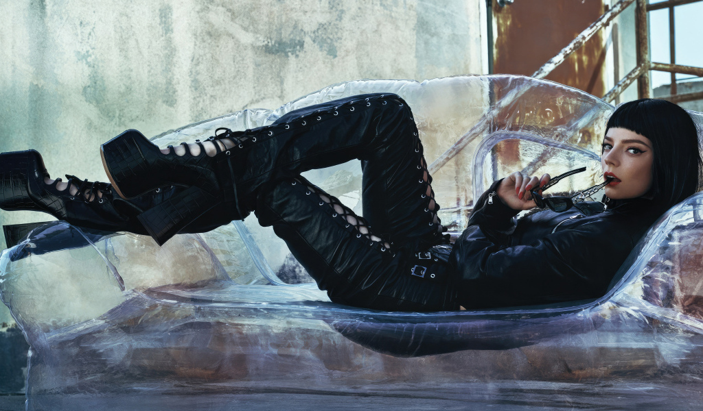 Актриса Аня Тейлор-Джой в черном костюме лежит на диване