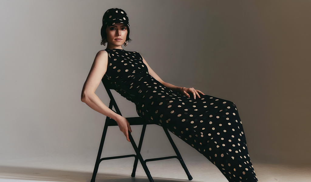 Актриса Дейзи Ридли в черном платье сидит на стуле