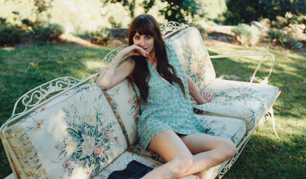 Актриса Дакота Джонсон в платье сидит на диване