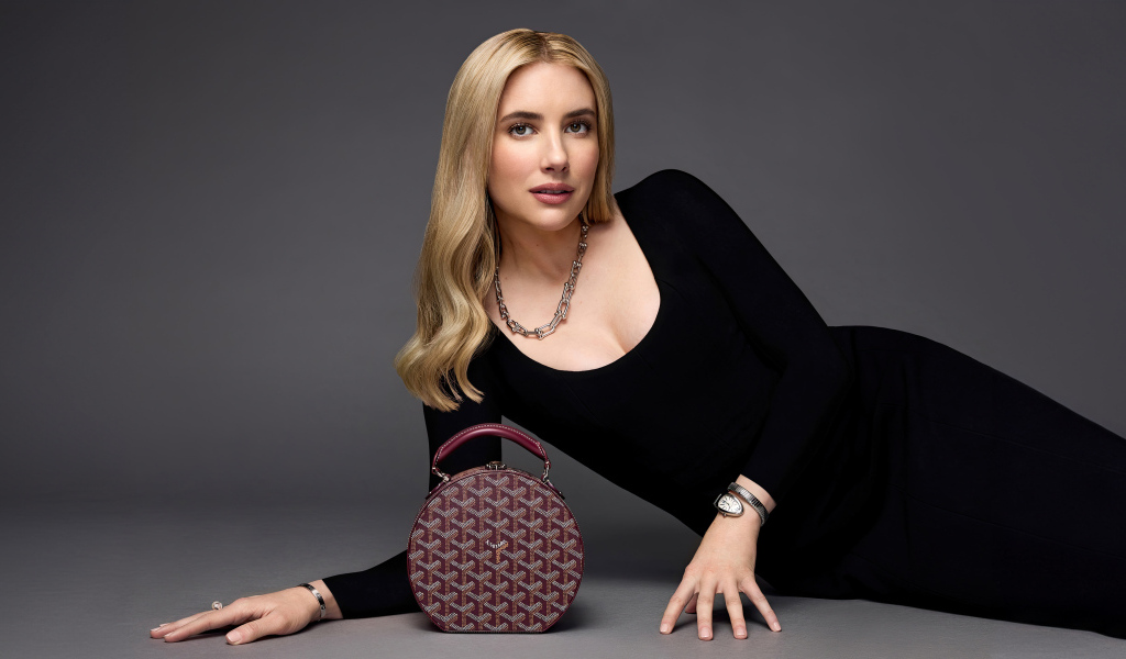 Актриса Эмма Робертс в черном платье с сумочкой лежит на сером фоне