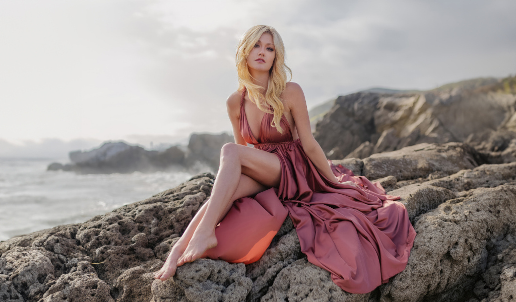 Актриса Кэтрин Макнамара сидит на камне у моря