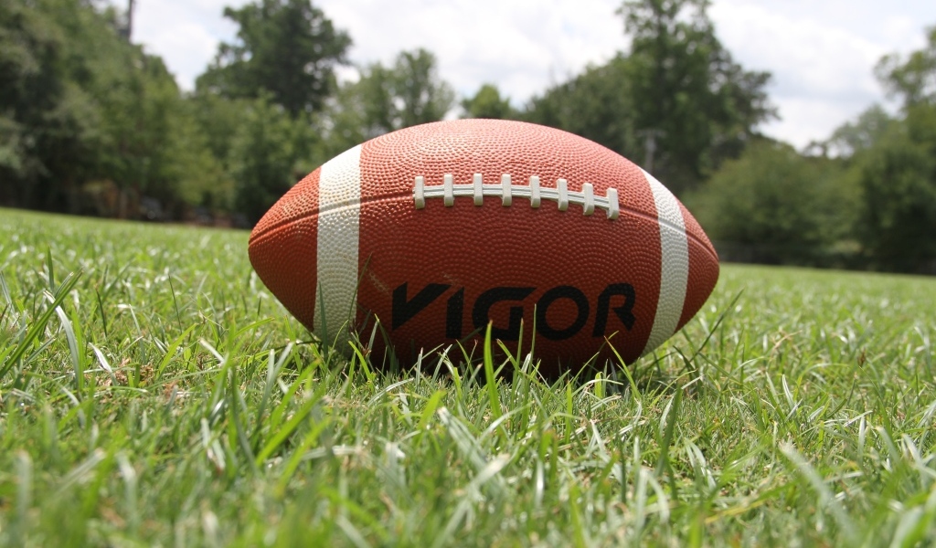 Мяч для американского футбола на зеленой траве 