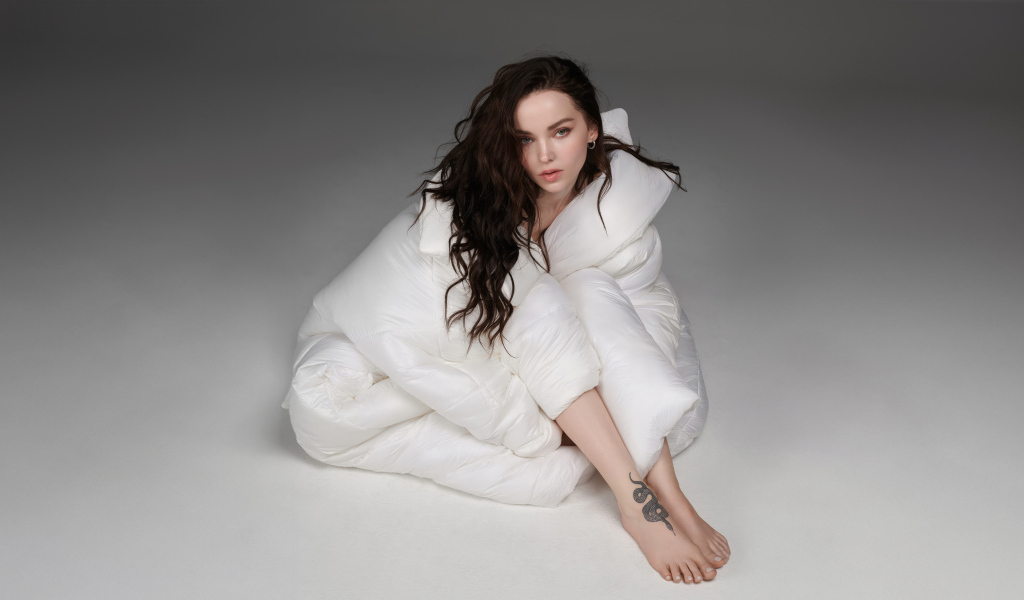 Красивая брюнетка Дав Кэмерон в белом костюме на сером фоне