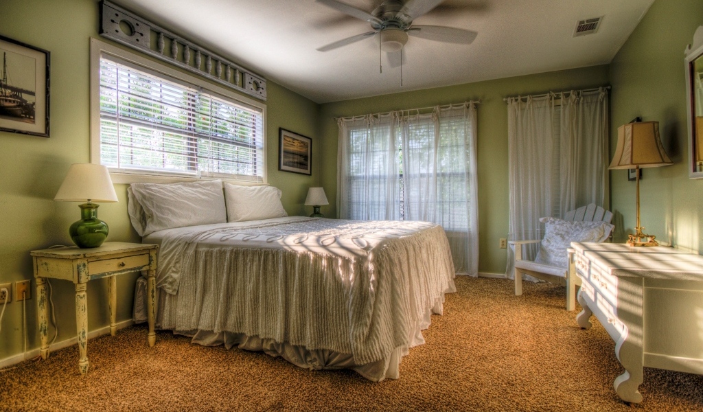 Спальня в зеленых тонах с высокой кроватью 