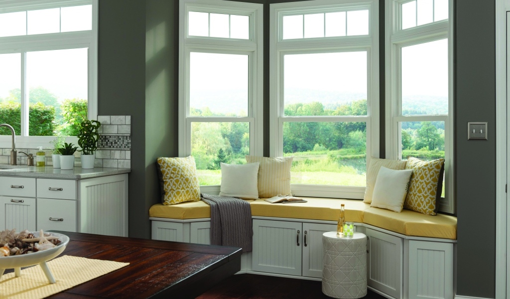 Уютная светлая кухня с эркером в загородном доме в зеленых тонах
