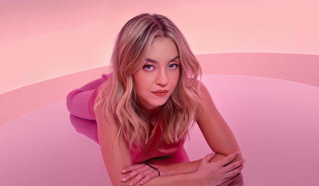 Милая блондинка Сидни Суини лежит на розовом фоне