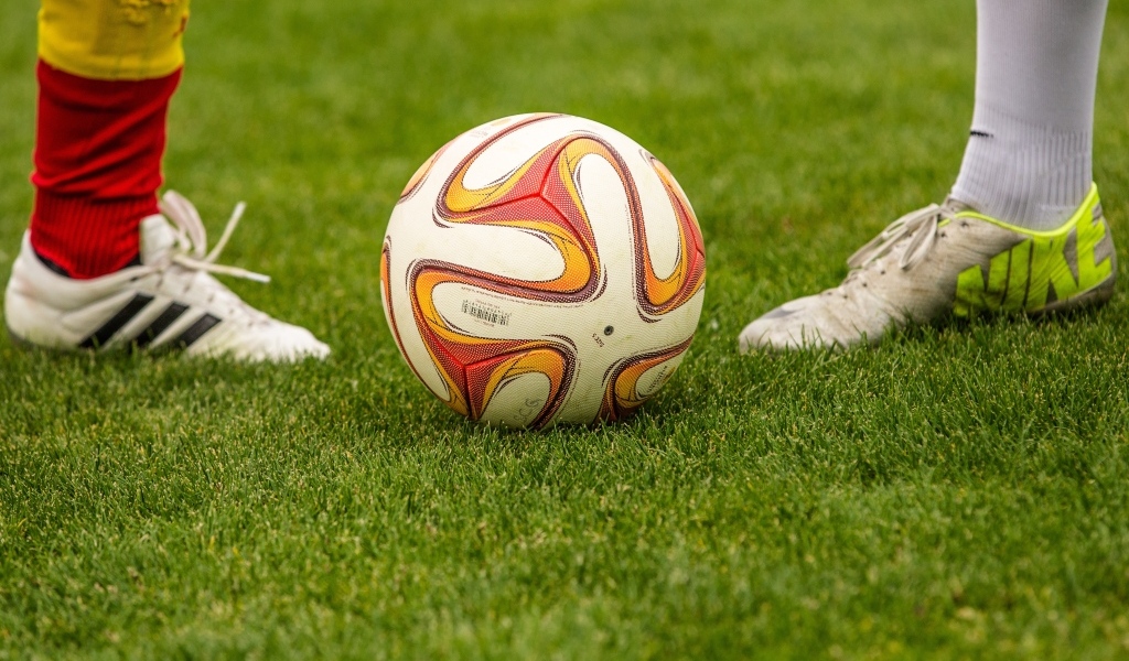 Футболисты с мячом на зеленой траве