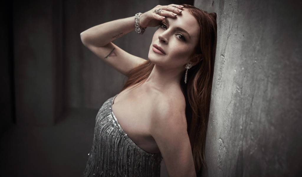 Рыжеволосая актриса Линдси Лохан стоит у стены