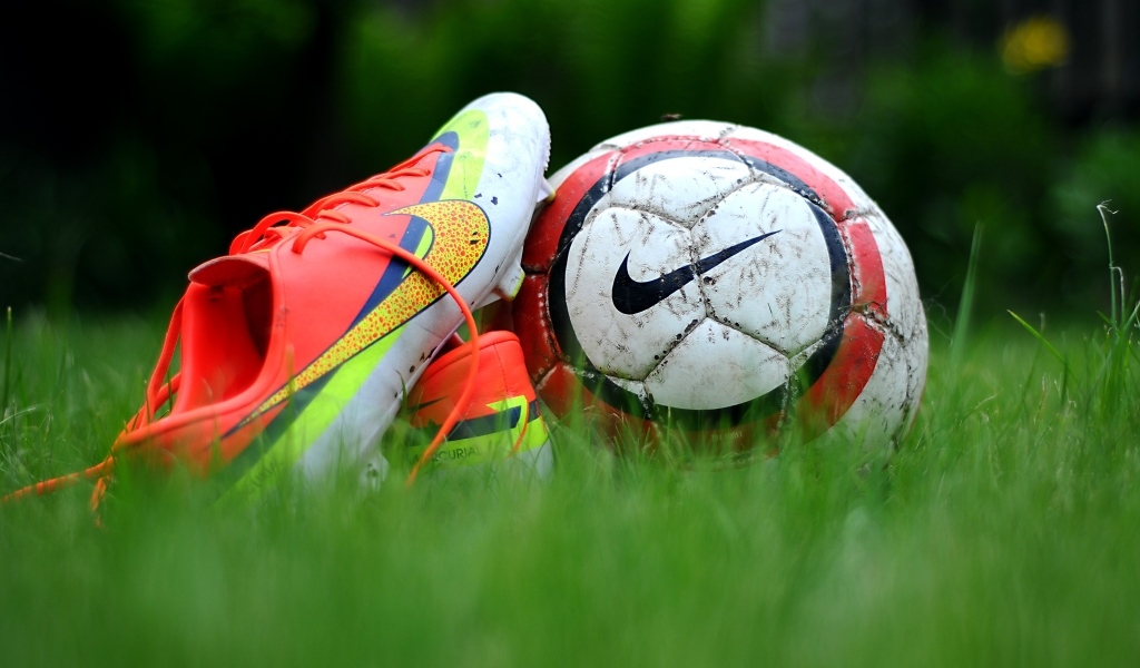 Футбольный мяч и бутсу на зеленой траве