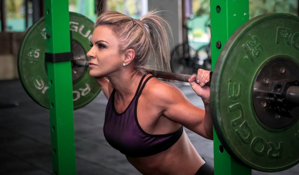 Сильная спортивная девушка поднимает штангу