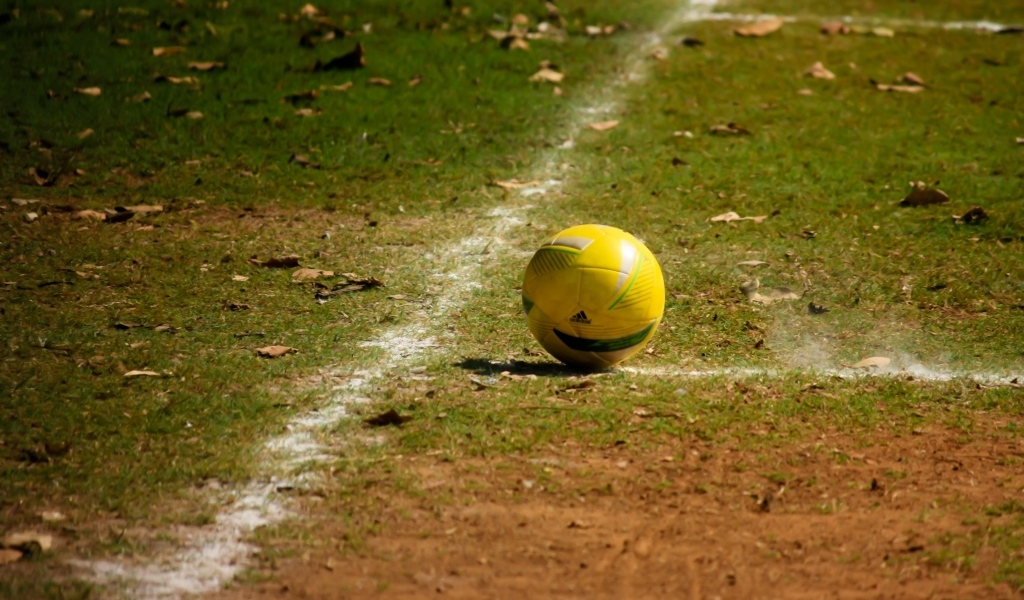 Желтый мяч на футбольном поле осенью 