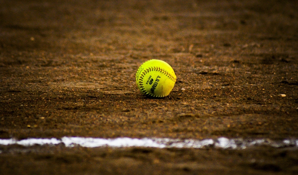 Желтый бейсбольный мяч на песке
