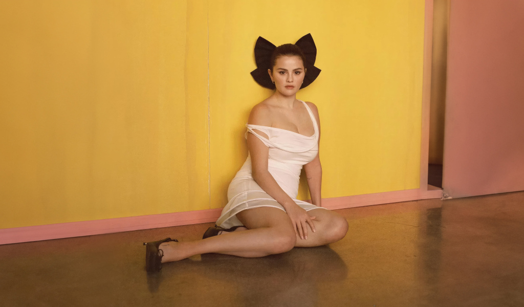 Молодая Селена Гомес сидит на полу у стены