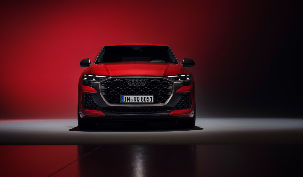 Вид спереди на автомобиль Audi RS Q8 performance 2024 года на красном фоне