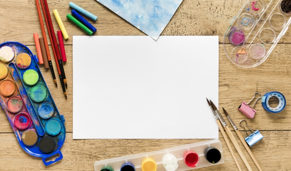 Предметы для рисования с листом бумаги на столе