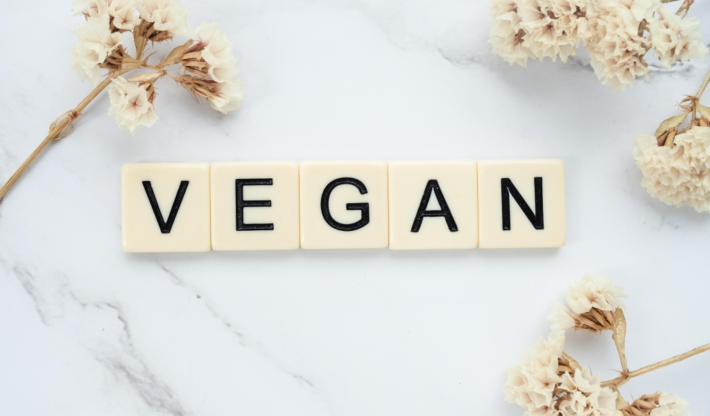Надпись веган на столе с цветами