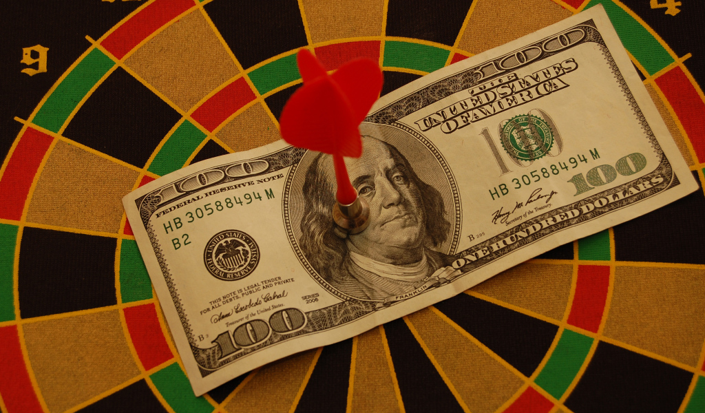 Купюра сто долларов на доске для дартс