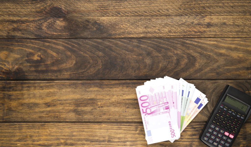 Купюры и калькулятор на деревянном фоне