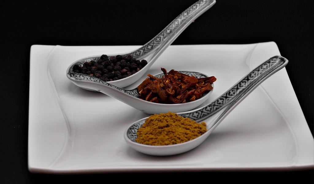 Ароматные специи в ложках на белой тарелке