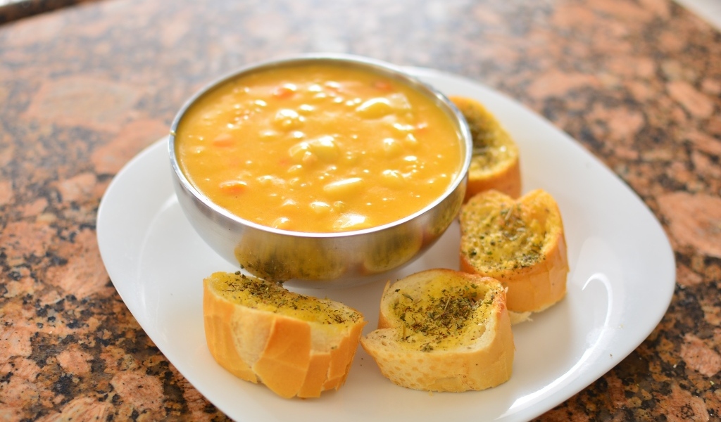 Суп с фасолью на тарелке с гренками