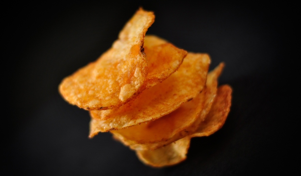 Хрустящие картофельные чипсы на черном фоне