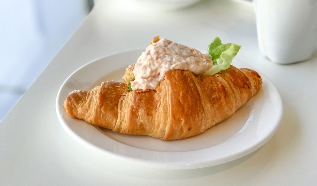 Круассан с начинкой на белой тарелке на завтрак 
