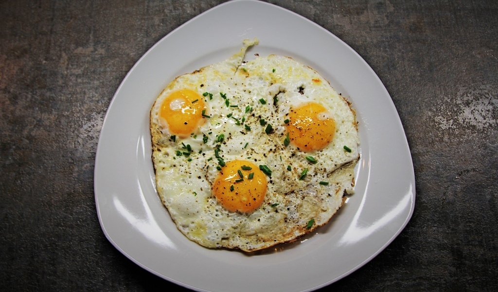 Яичница глазунья в тарелке на сером столе