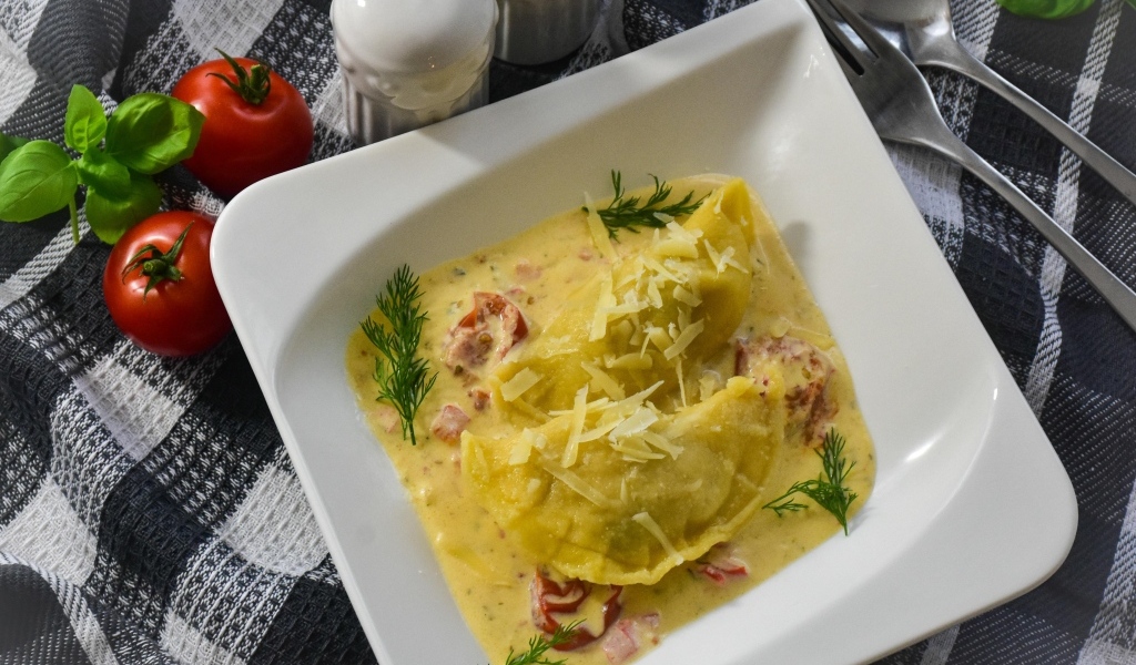 Равиоли с соусе с беконом на тарелке