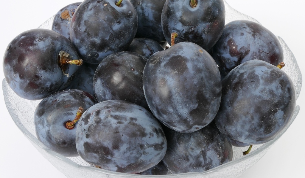 Стеклянная тарелка с вкусными синими сливами