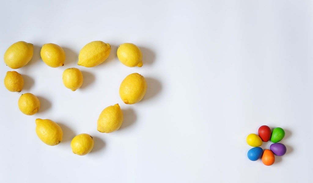 Сердце из желтых лимонов на сером фоне с конфетами