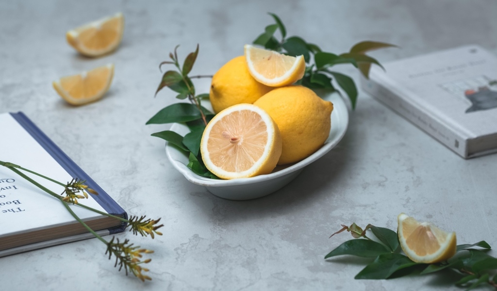 Лимон с зелеными листьями на столе с книгами