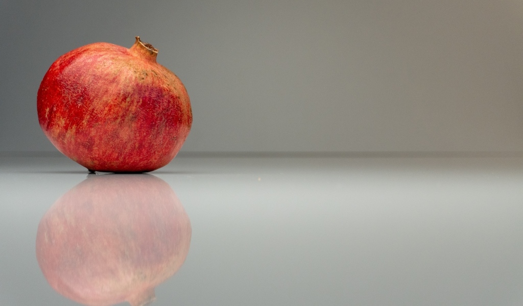 Красный гранат отражается в поверхности на сером фоне