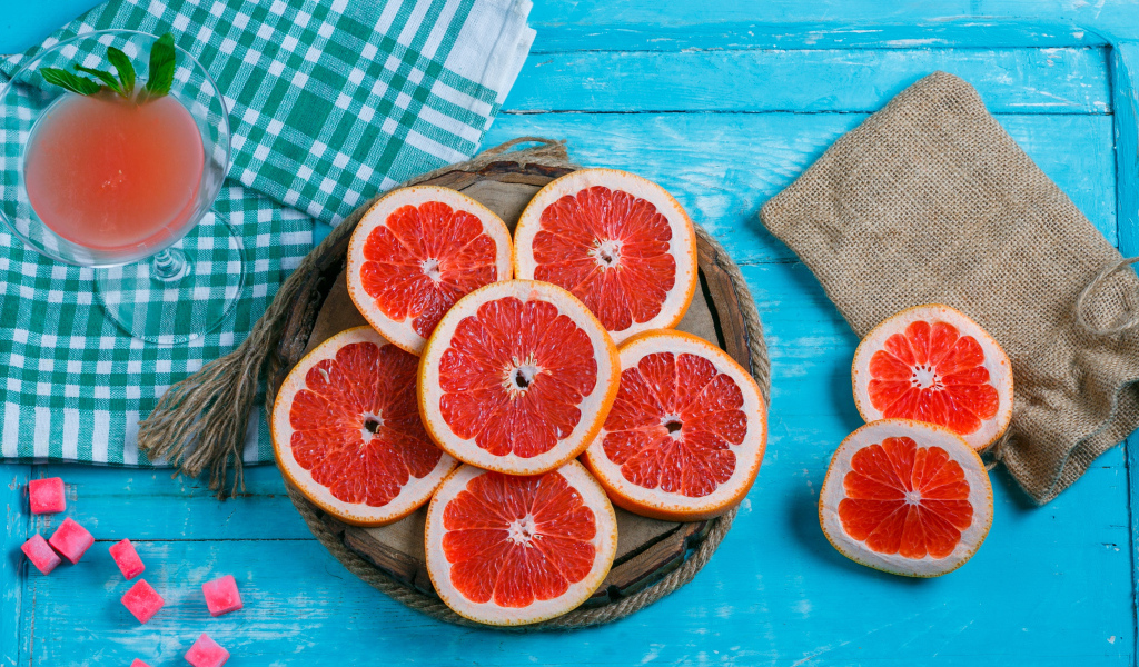 Нарезанный грейпфрут с соком на голубом столе