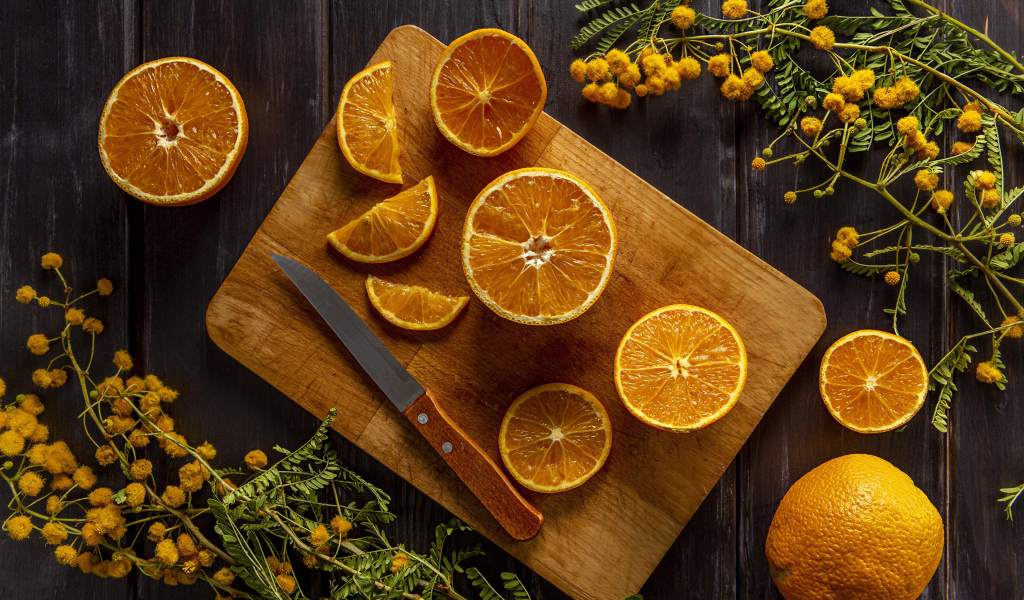 Нарезанный апельсин на доске на столе с цветами