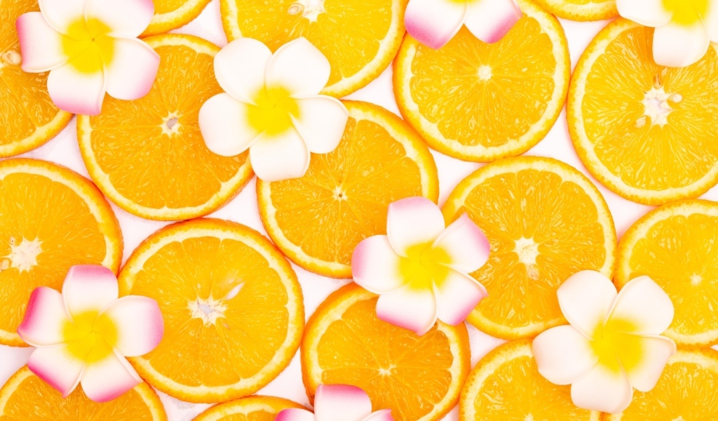 Нарезанный апельсин с цветами плюмерии для фона