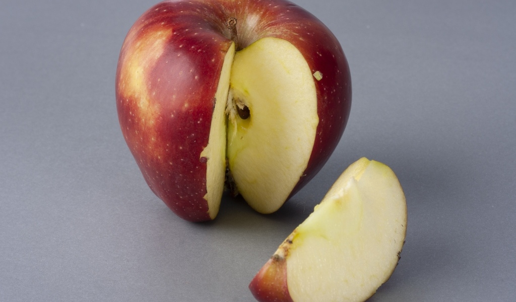 Разрезанное красное яблоко на сером фоне