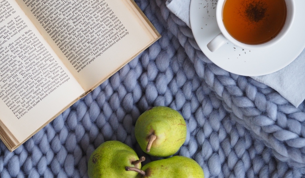 Три зеленые груши на столе с чаем и книгой