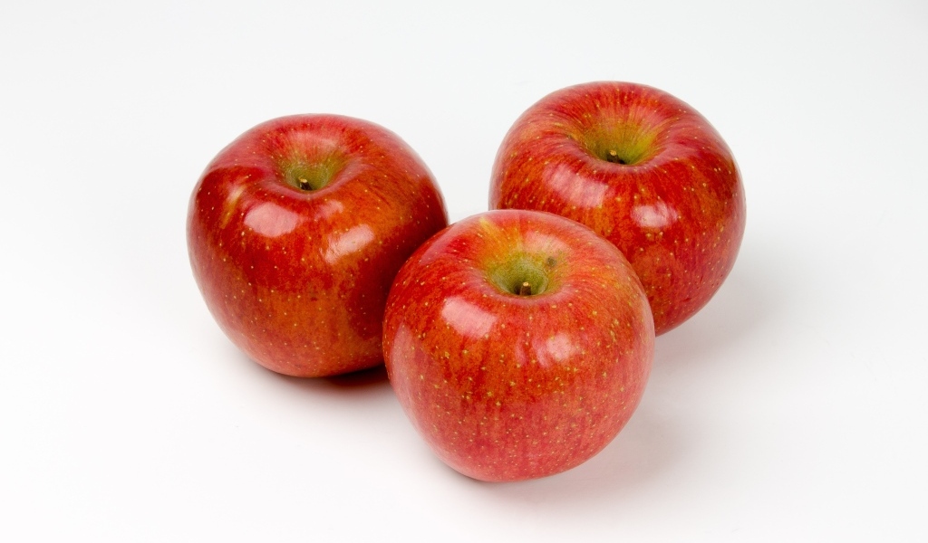 Три красных яблока на белом фоне