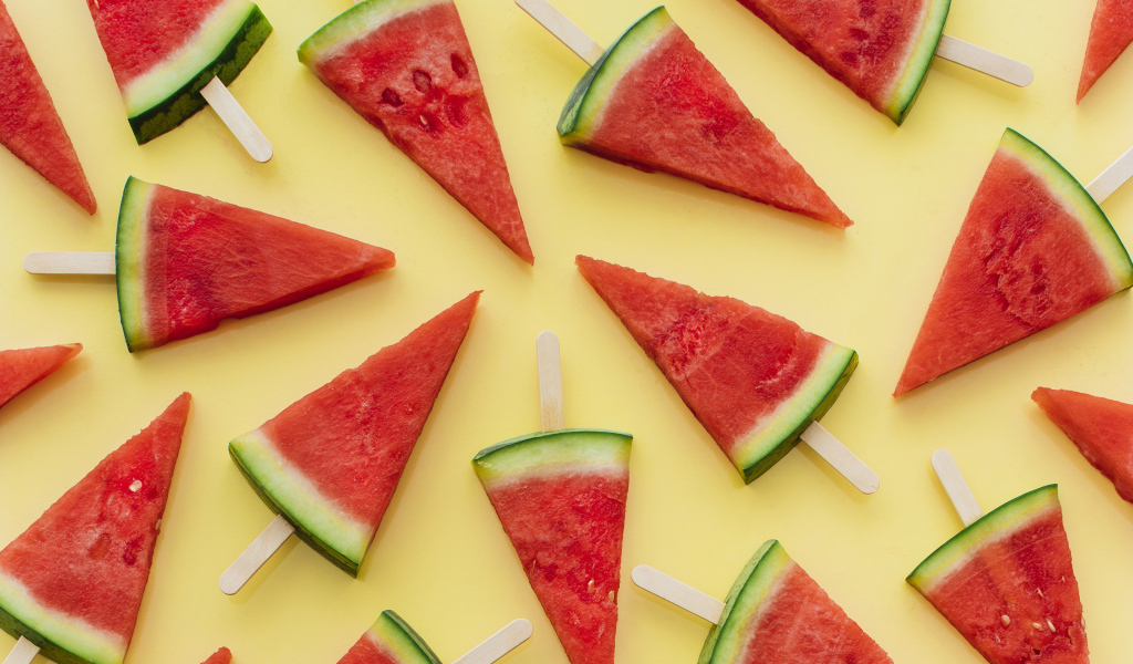 Куски арбуза на палочке на желтом фоне