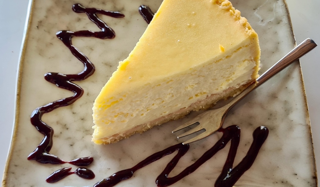 Кусок чизкейка с шоколадным топпингом на тарелке