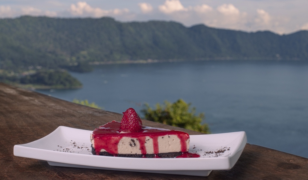 Кусок чизкейка с клубничным джемом на фоне моря