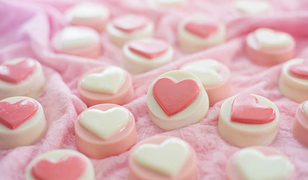 Конфеты с сердечками на розовой поверхности