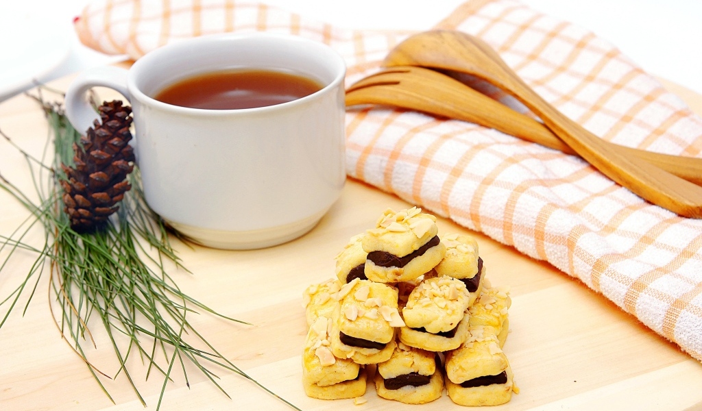 Печенье с чашкой чая и сосновой шишкой на столе