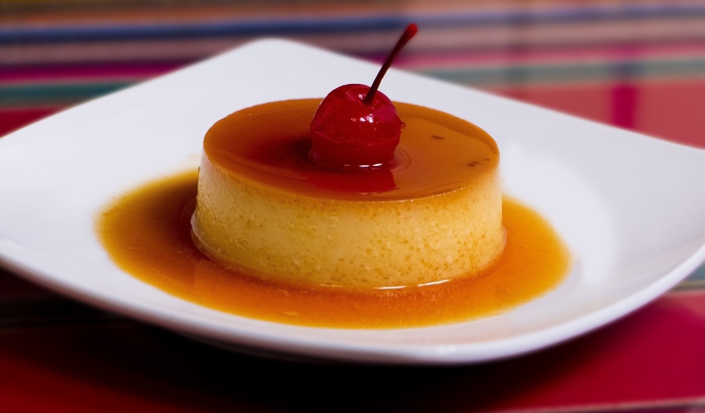 Десерт с сиропом и черешней на белой тарелке