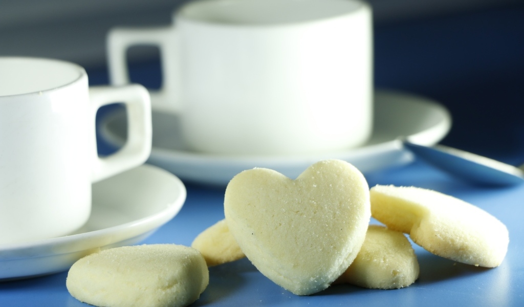 Сладкое печенье в форме сердца с кружками на столе