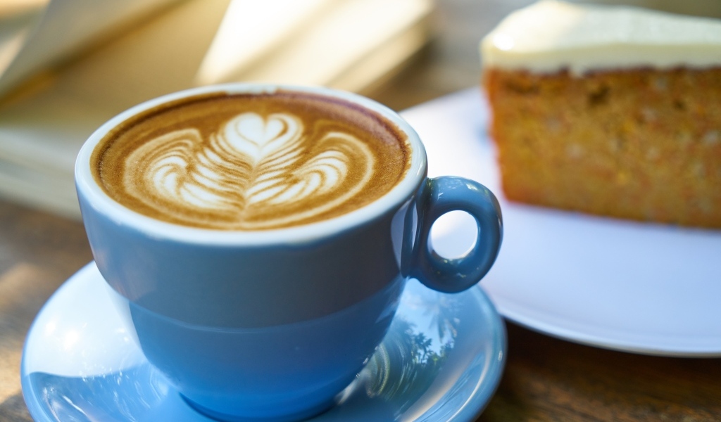 Чашка ароматного горячего кофе с рисунком на пене на столе на завтрак